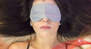 kobieta śpiąca w łóżku z szarą maską na oczach