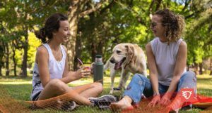 dwie kobiety siedzące w parku z labradorem w naturalnym świetle