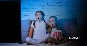 Dzieci oglądające telewizję, które powinny nosić okulary blokujące światło niebieskie