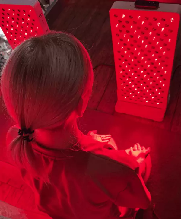 Kobieta podczas naświetlania lampą na podczerwień RedBoost od EyeShield